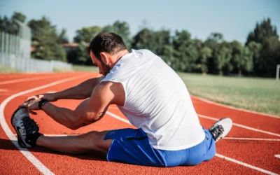 Man stretching on a running track, emphasizing physical therapy and injury recovery in sports.